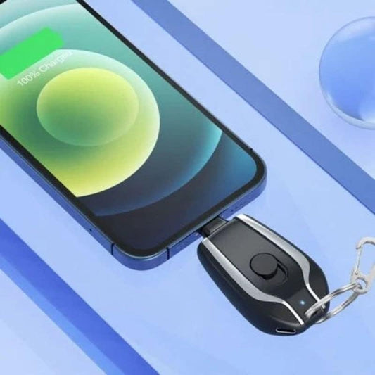 Mini keychain portable charger attached to a set of keys while charging a smartphone
