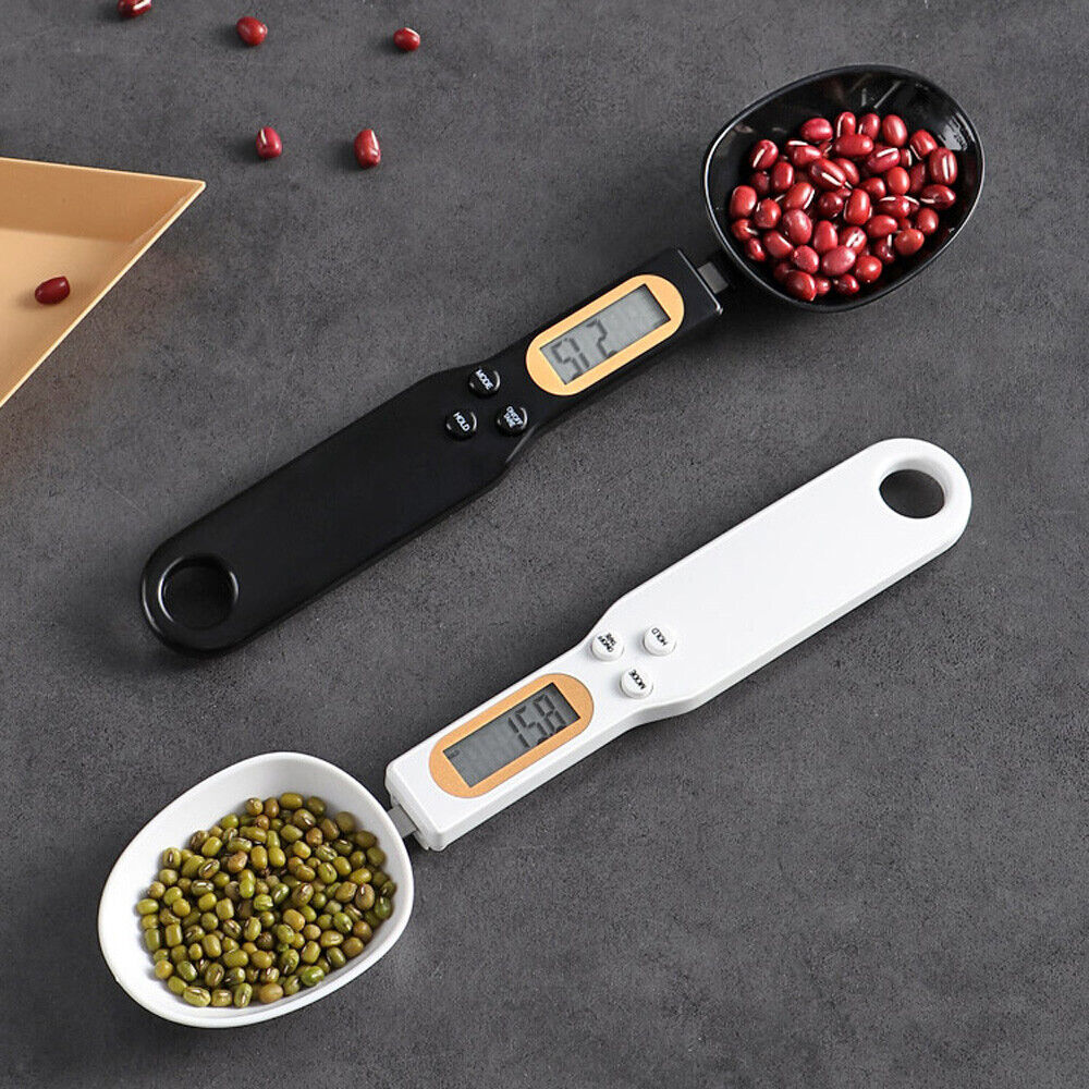 Digital kitchen scale spoon with LCD display measuring ground coffee beans on a wooden kitchen worktop